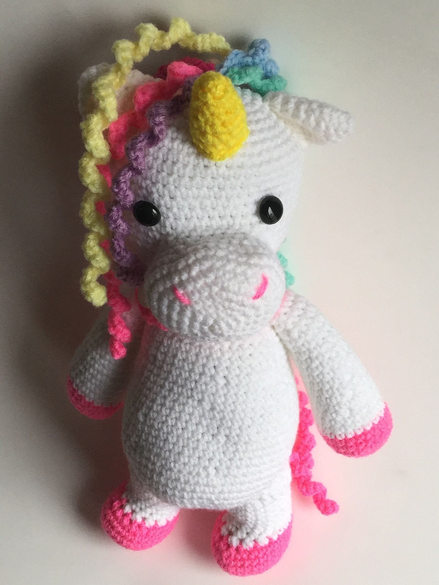 A white crocheted unicorn with a rainbow mane