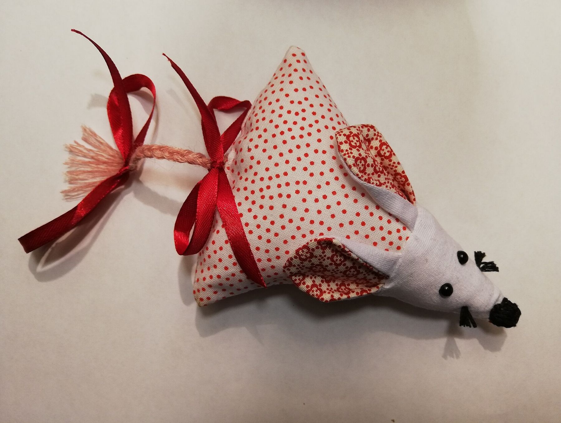 A polka-dot fabric mouse with a red ribbon tail