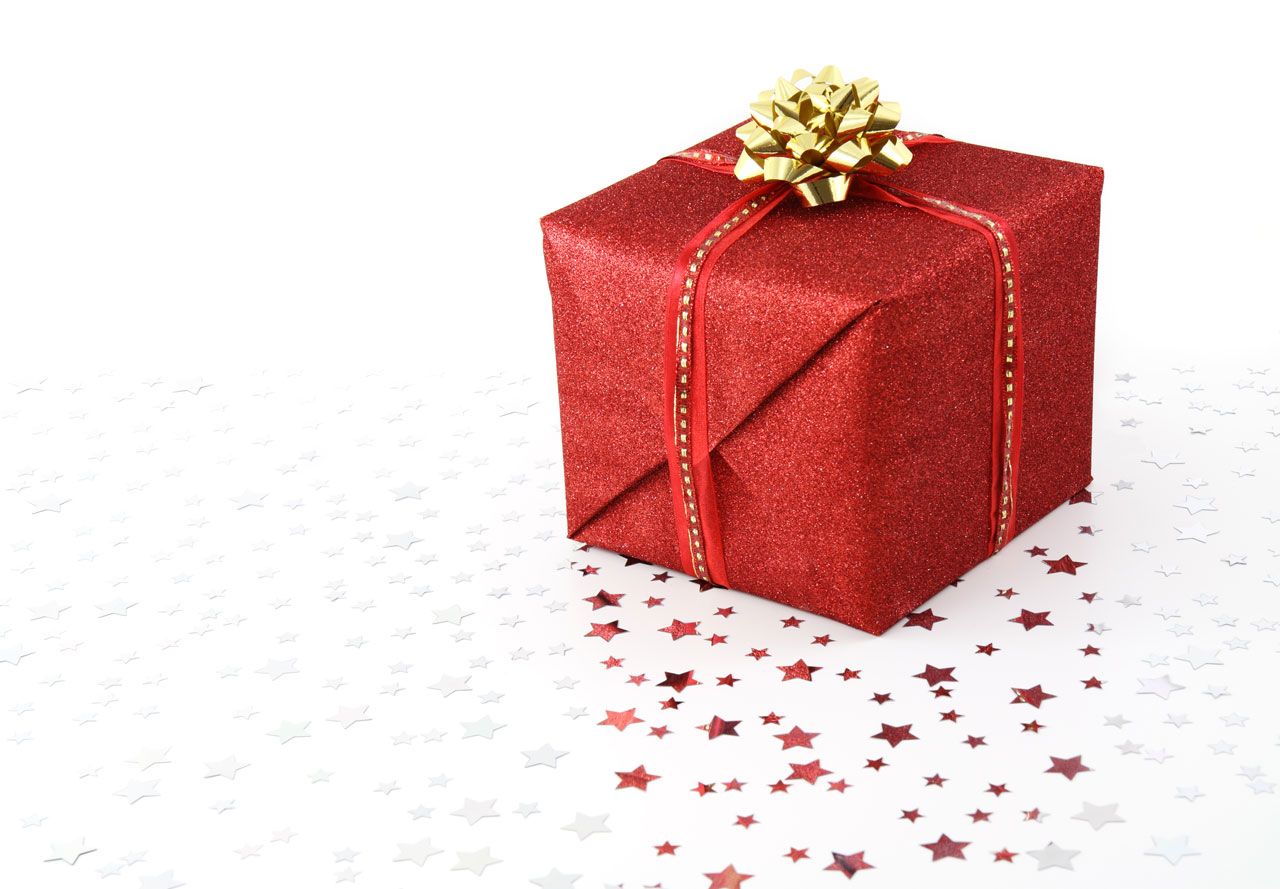 A red wrapped gift with a gold bow on star confetti