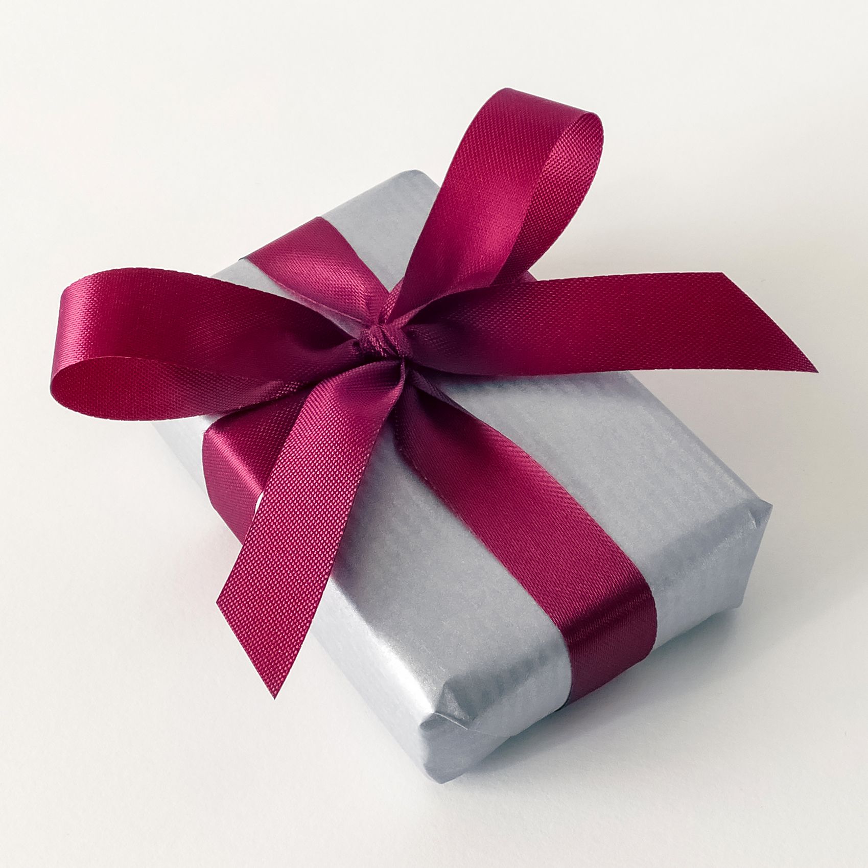 A silver-wrapped gift with a burgundy satin bow