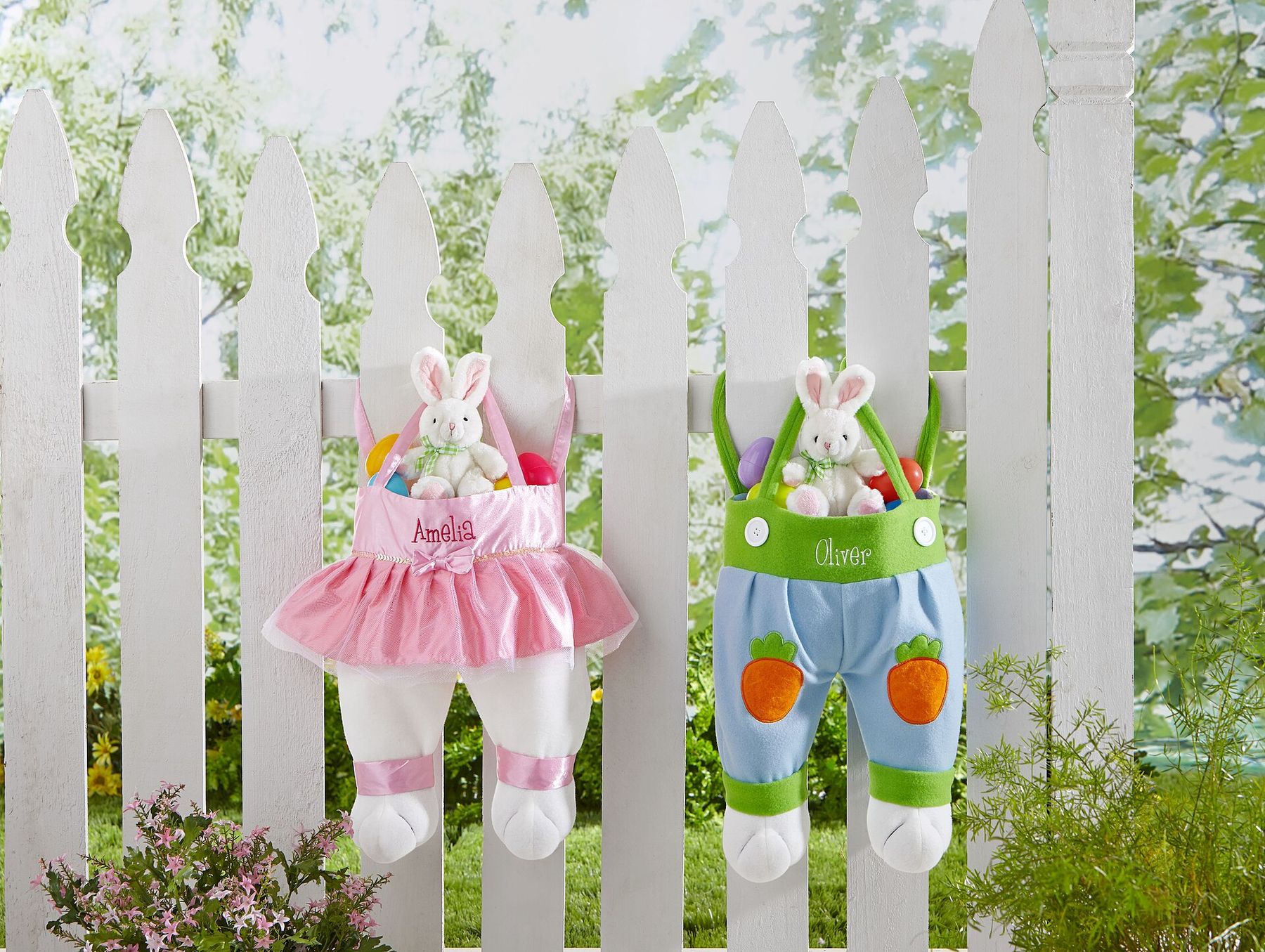 Two bunny-themed baskets with small plush bunnies hanging on a white picket fence