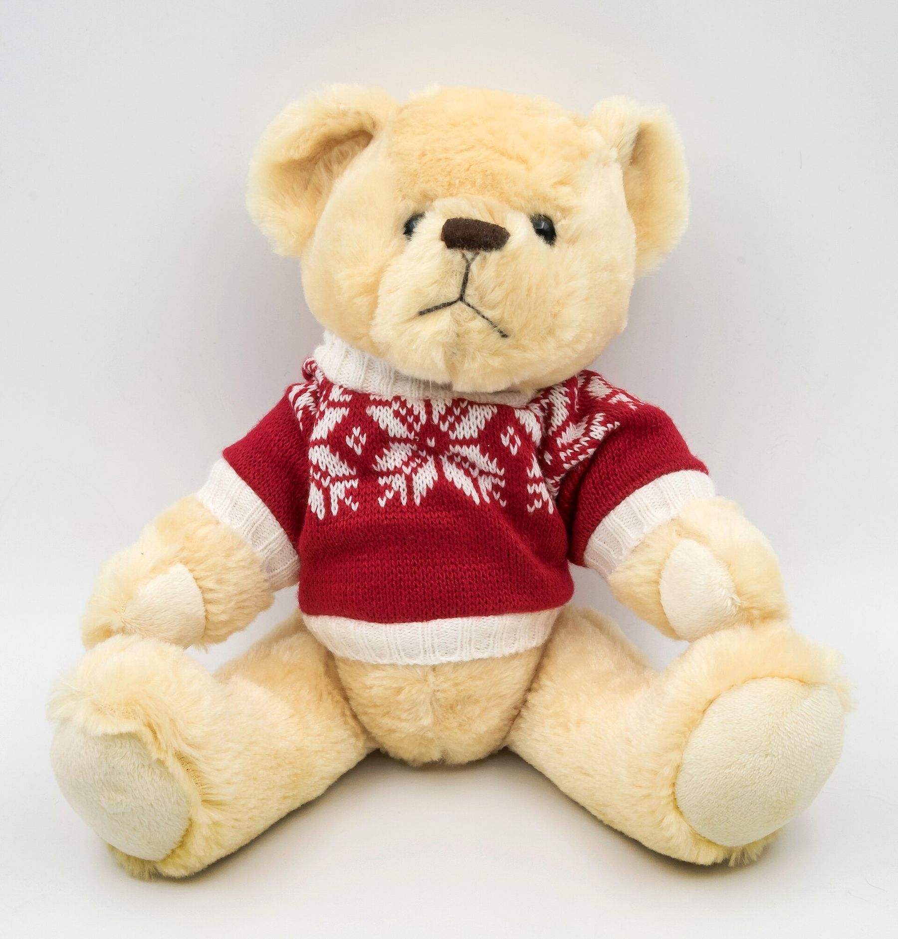 A cream teddy bear in a red Nordic sweater